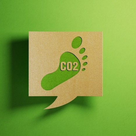 Carbon footprint icon on a chat bubble which is made of recycled paper on green background. Horizontal composition with copy space.